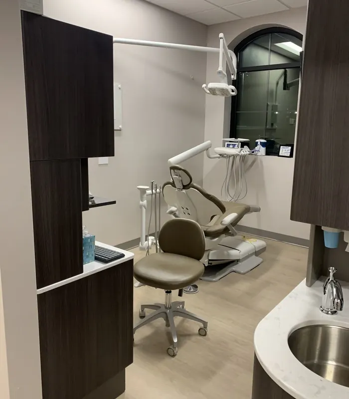 A treatment room with its dental chair beneath an arched window.